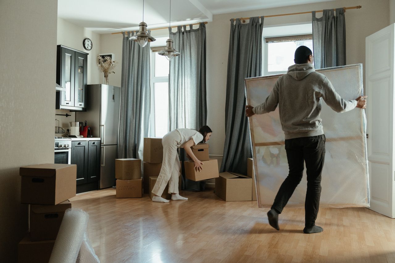A young couple unpacks boxes in their new apartment and arranges their belongings.
